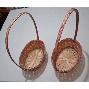 Two vintage woven bamboo baskets with‎ tall handles and pink accenting.